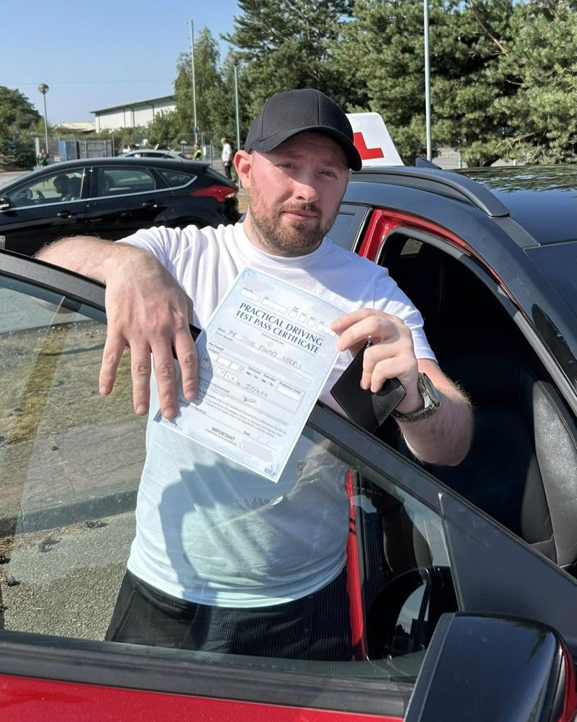 Adult learner with his pass certificate leaning on the door of the Hallwood Training Services car