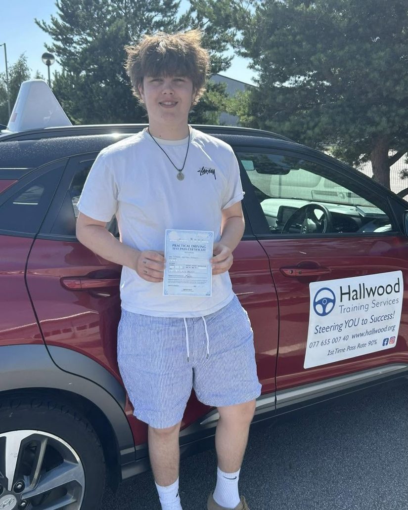 Learner standing beside the branded Hallwood Training Services car holding a pass certificate