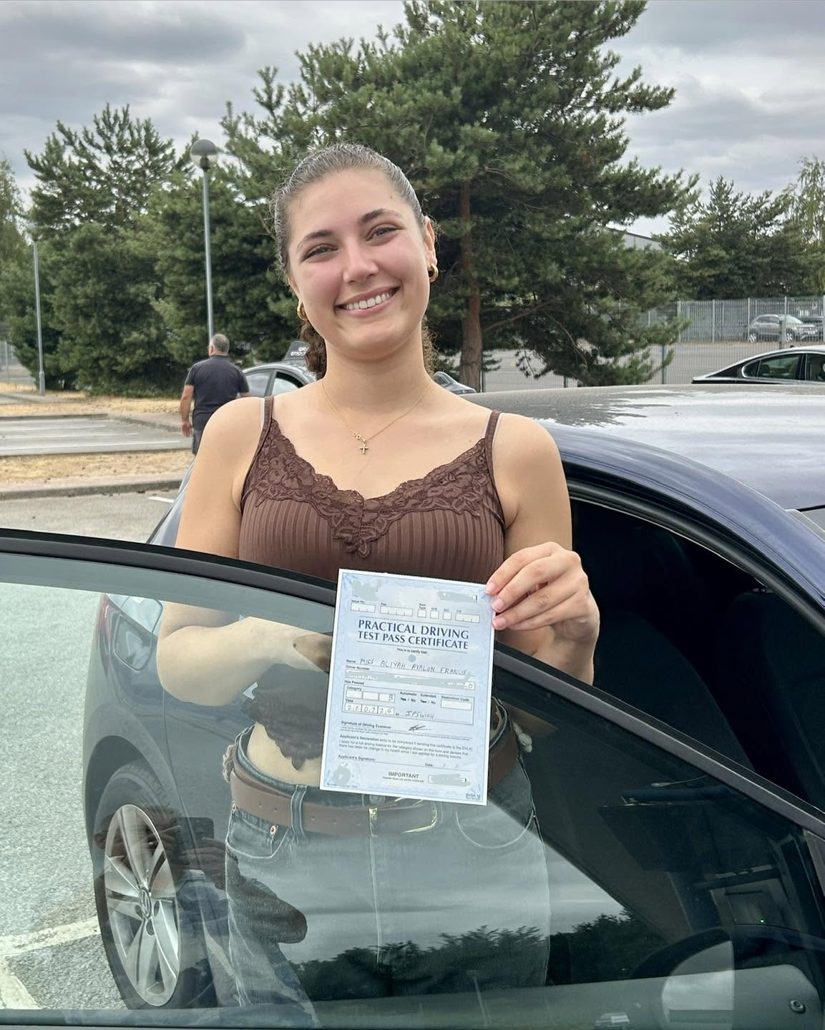 Learner holding her pass certificate by the car door in the Ipswich driving test centre car park