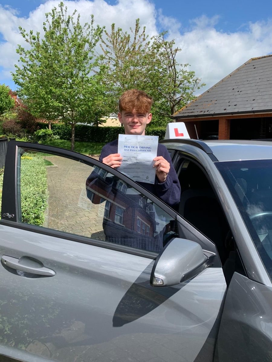 Learner holding his driving test pass certificate over the open car door on a sunny day