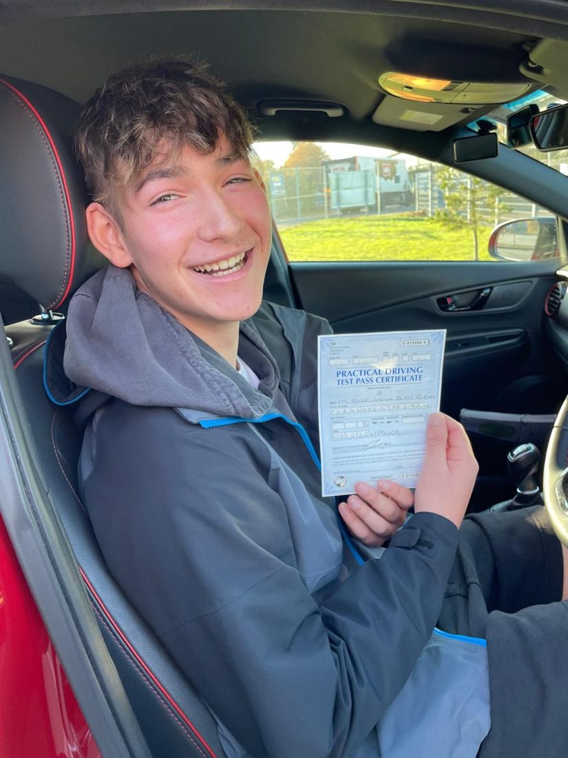 Delighted learner in the driver's seat of the Hallwood Training Services car holding his pass certificate