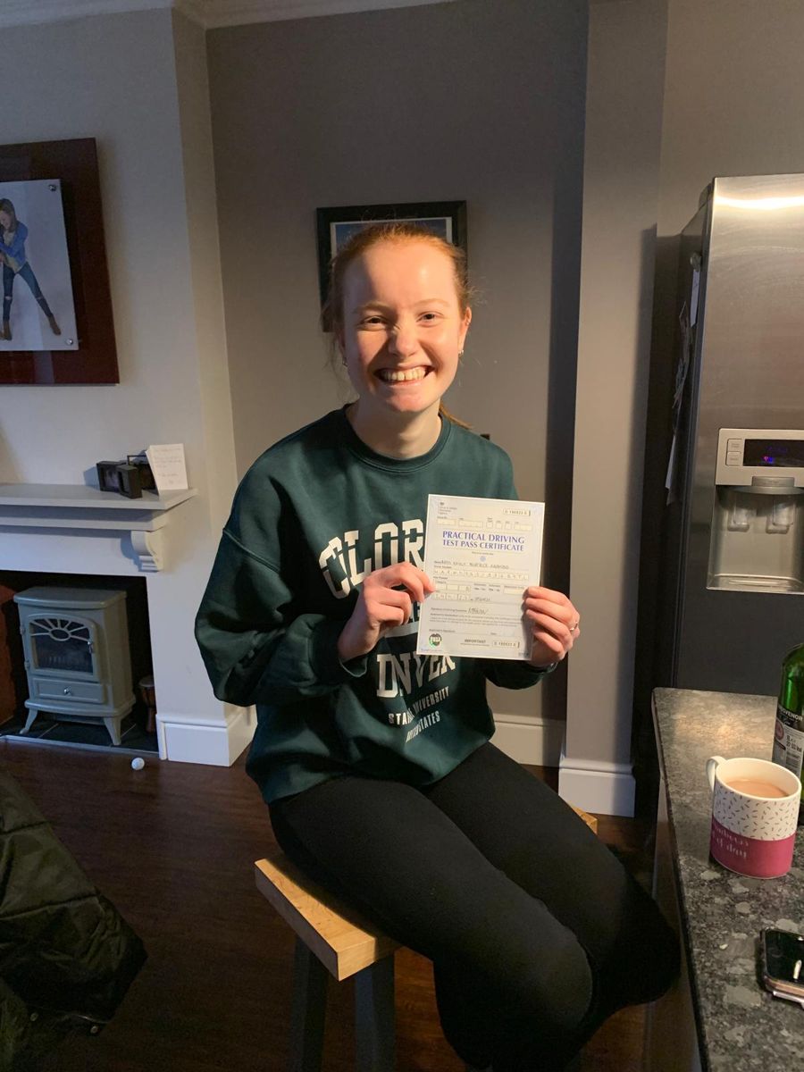 Pupil smiling at home with her practical driving test pass certificate