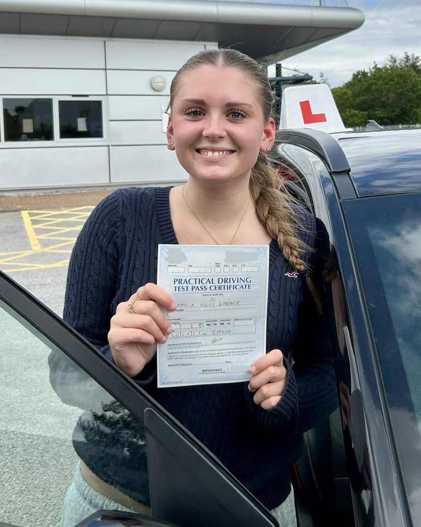 Pupil holding up her practical driving test pass certificate outside the Ipswich test centre, where Woodbridge learners take their test